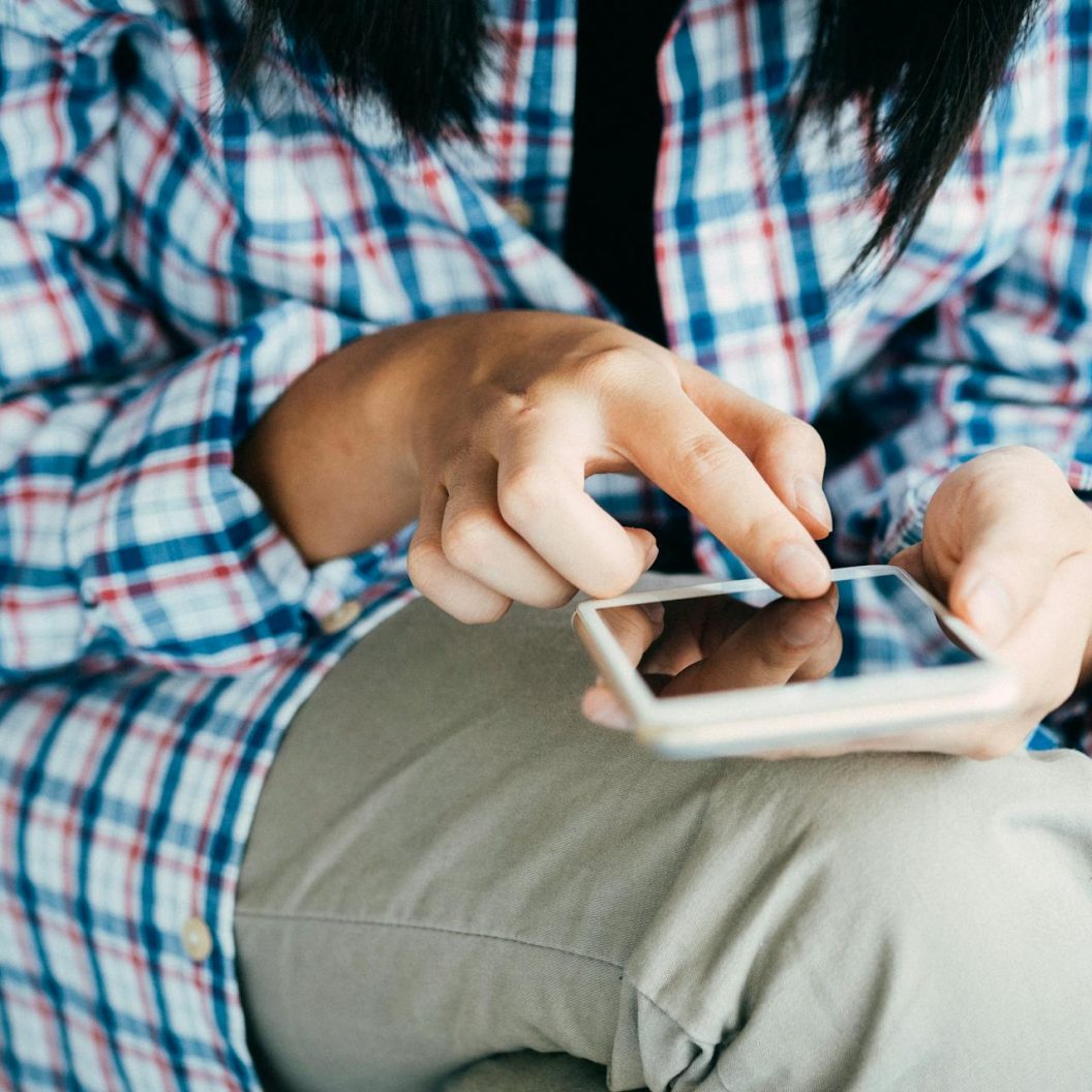 personne vêtue d'une chemise à carreaux sur son smartphone